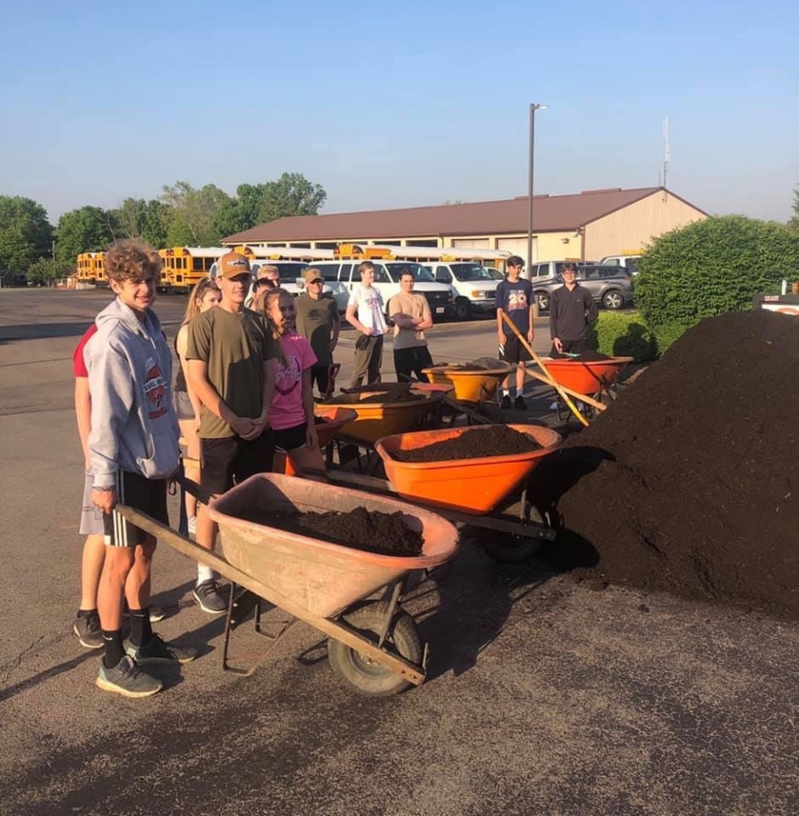 kids holding wheelbarrows full of mulch